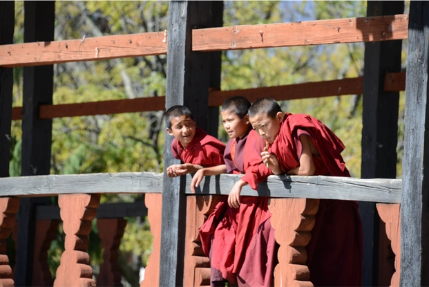 Young Monks overlooking from a cantilever bridge in Punakha